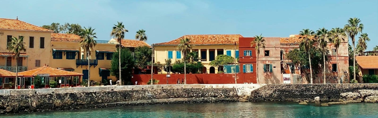 A row of colorful houses lined with palm trees along a beach